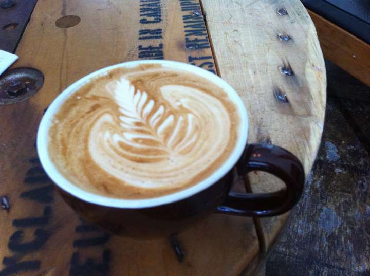 A cup of coffee sitting on top of a wooden table.