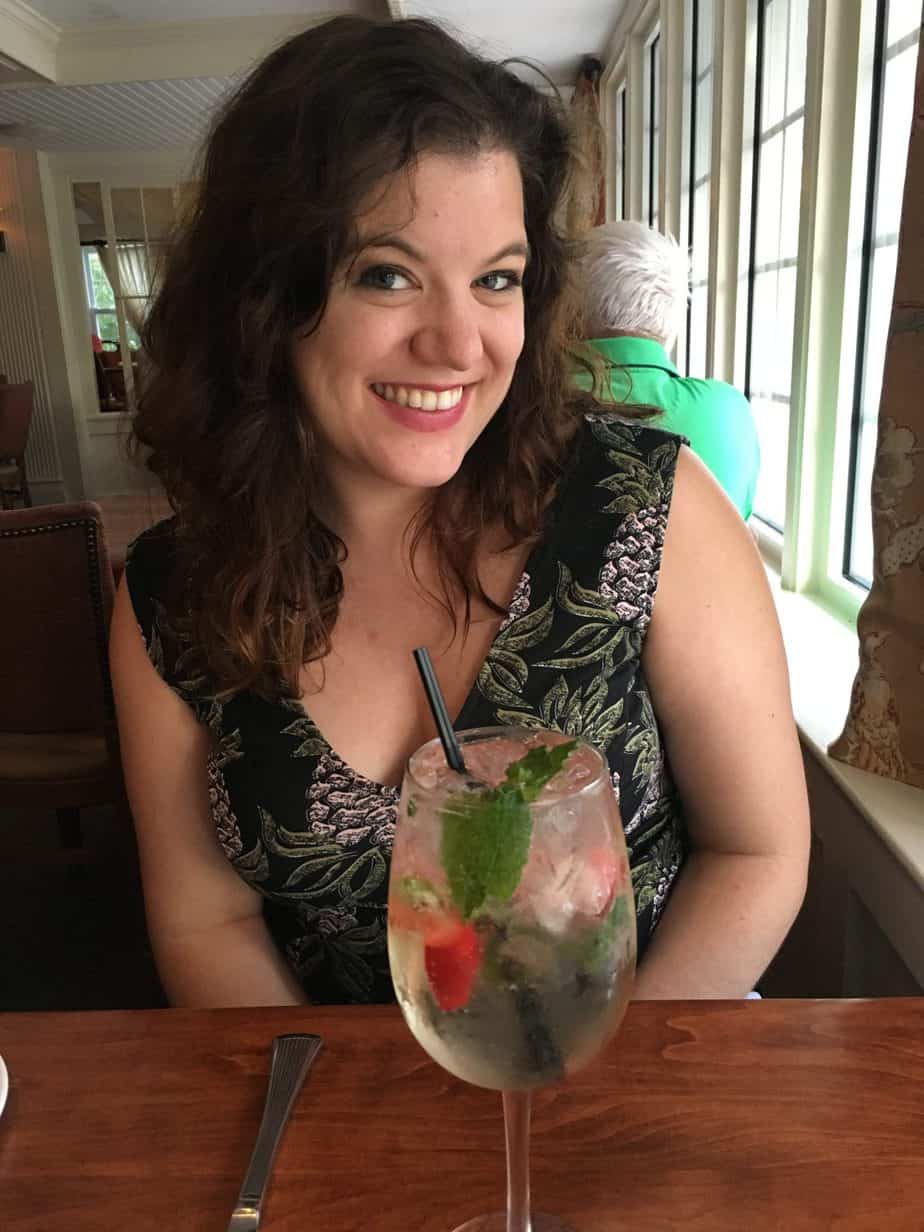 A woman poses with a drink in front of her.