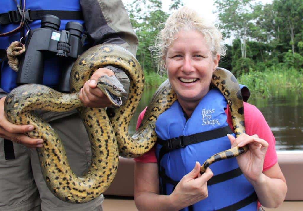 A woman poses while holding a snake.