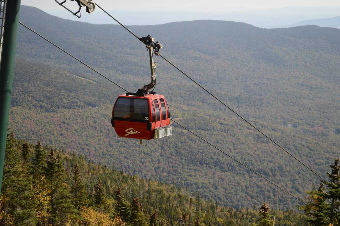 A red gondola floats high above the mountains. 