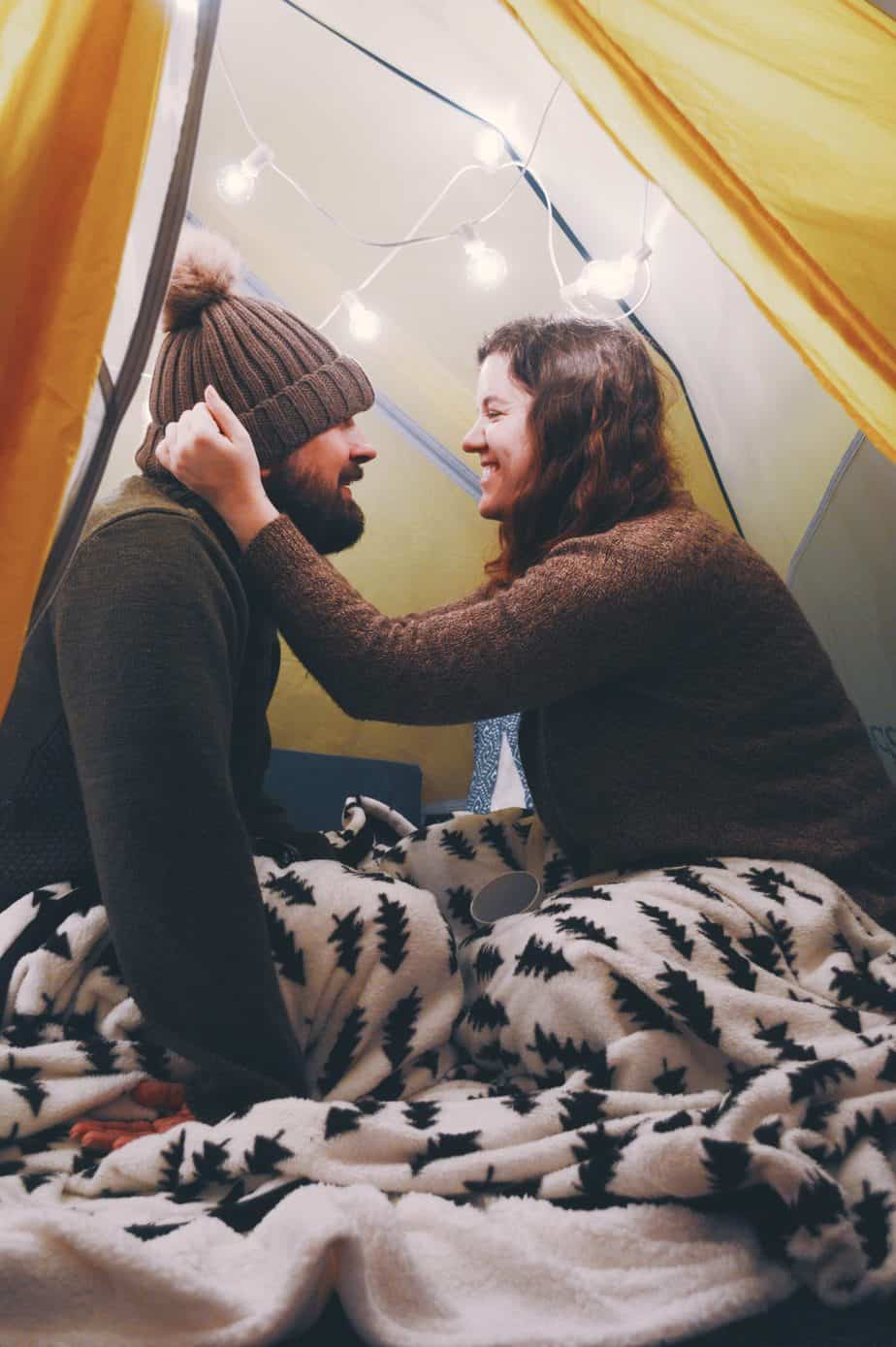 A couple smiles at each other while sitting on the ground.