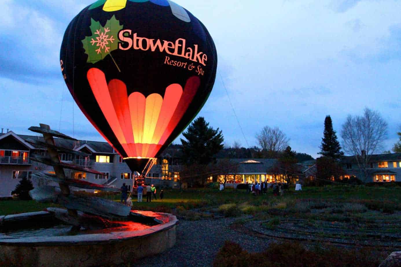 People stand around a hot air balloon that says Stoweflake Resort & Spa.