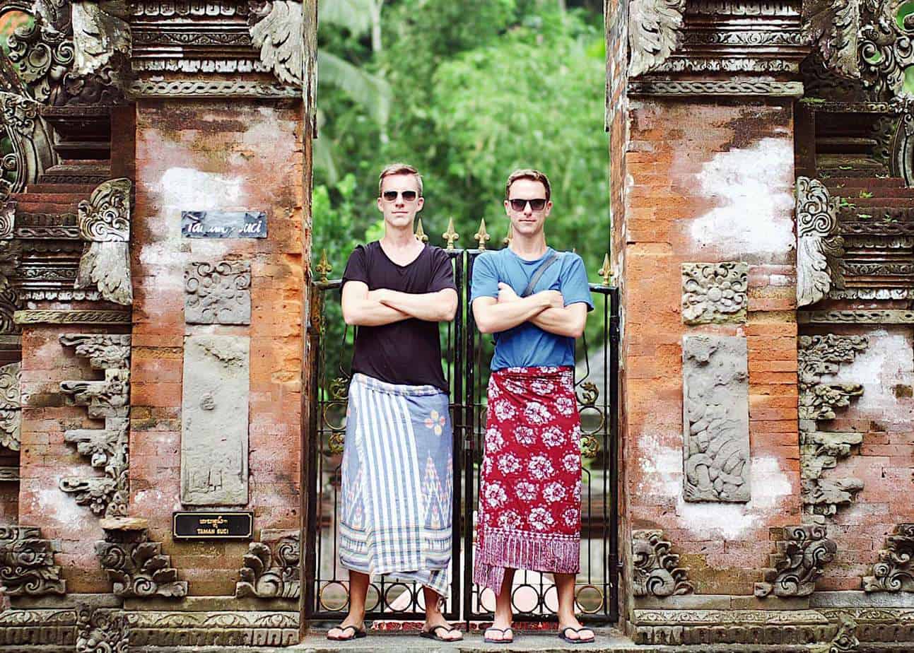 A couple poses in front of a fence.
