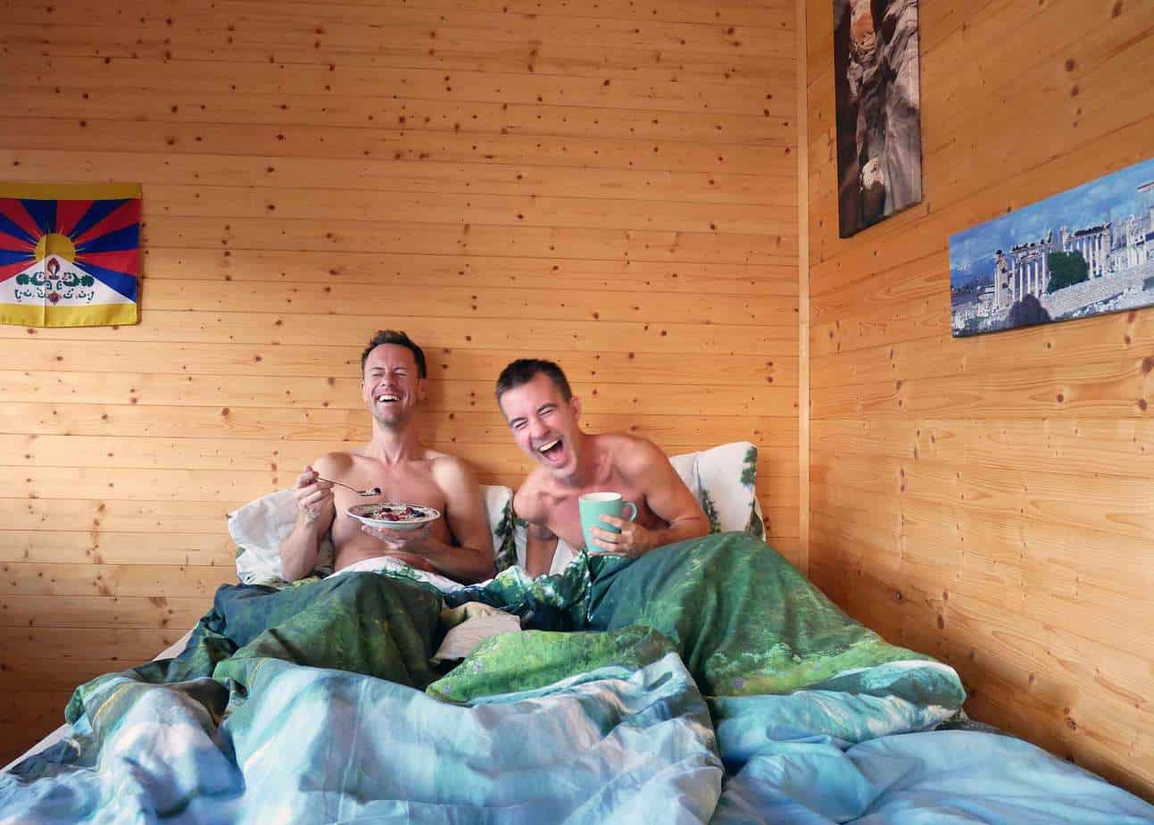 A couple laughs while eating in bed.