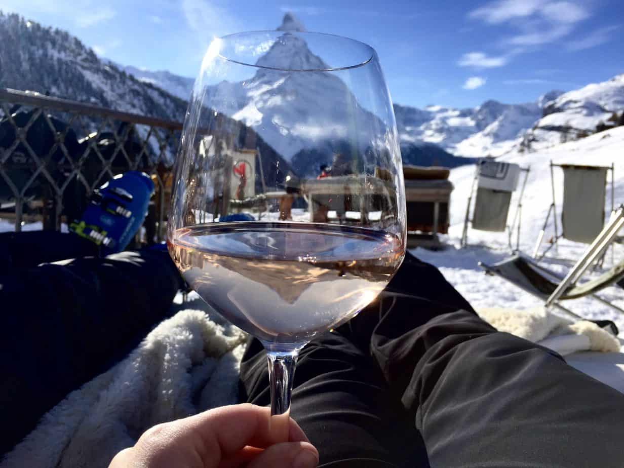 A view of a snowy vacation spot through a wine glass.