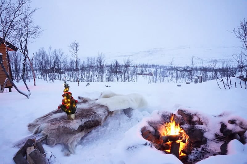 A wintery snowscape in Norway with a firepit outside