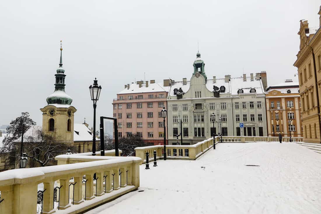 Several colorful buildings in the snow under a grey sky.