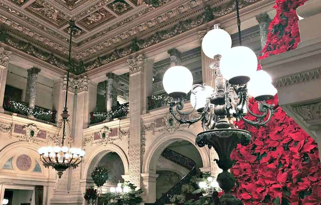 Interior photo of historic architecture inside a mansion. Tall chandeliers hang from the ceilings, illuminating the room.