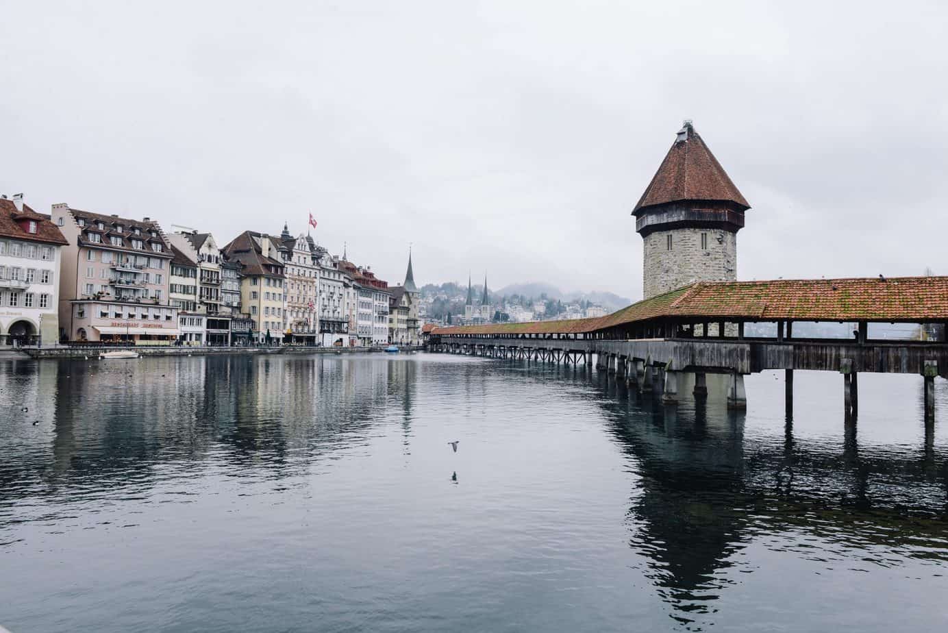 Switzerland on a grey day near the water with buildings on one side and a pier on the other