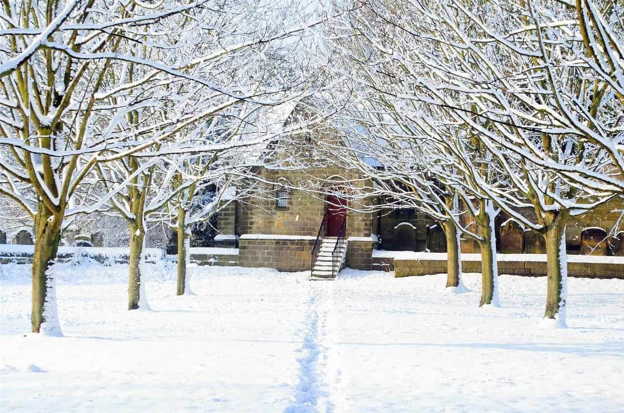 A snowy path trampled with footprints leads to a brick building in winter.