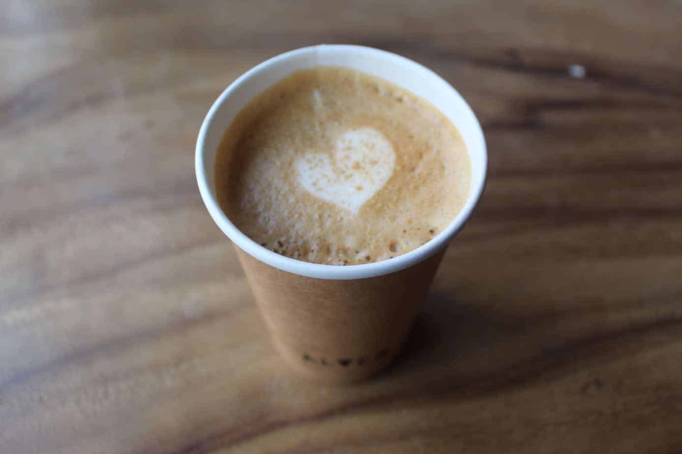 Close up of a cup of coffee with a white heart on it.