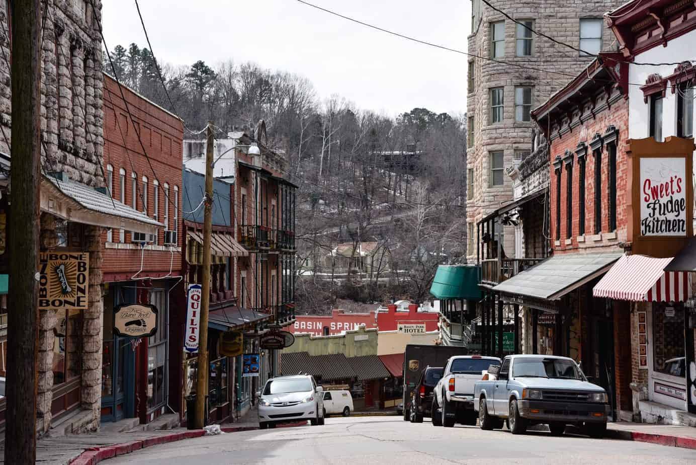 A small street curving down a hill with local shops on each side of the road. 