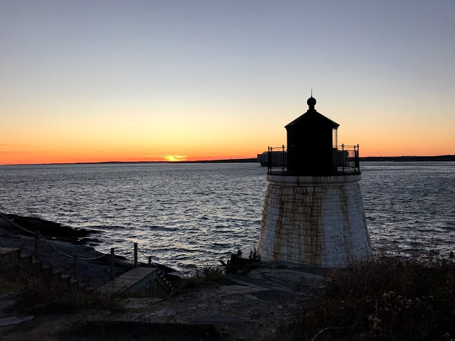 A lighthouse near the water at sunset.