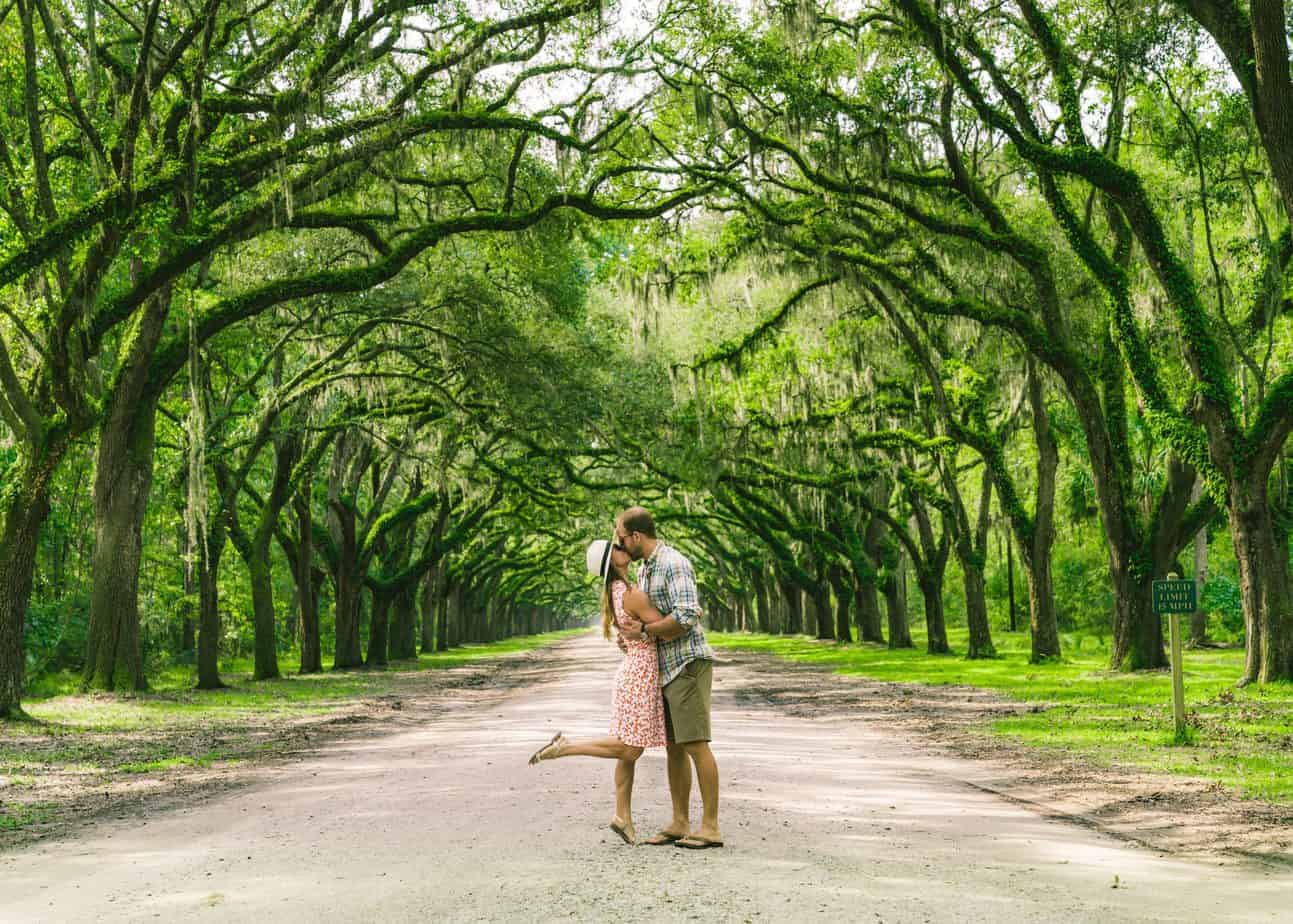 A couple kisses under a lane of Live Oaks in romantic Savannah Georgia