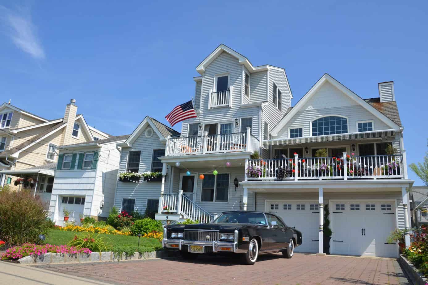 A car parked in front of a large white house decorated with balloons. 