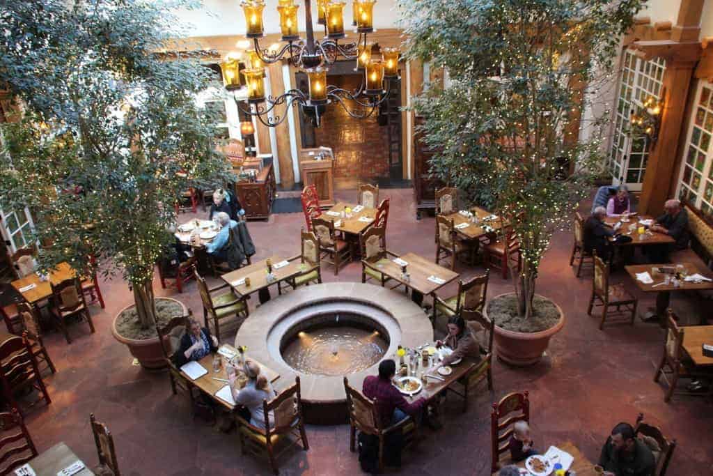 An aerial view of a romantic restaurant with potted plants, chandeliers, and wooden tables and chairs.