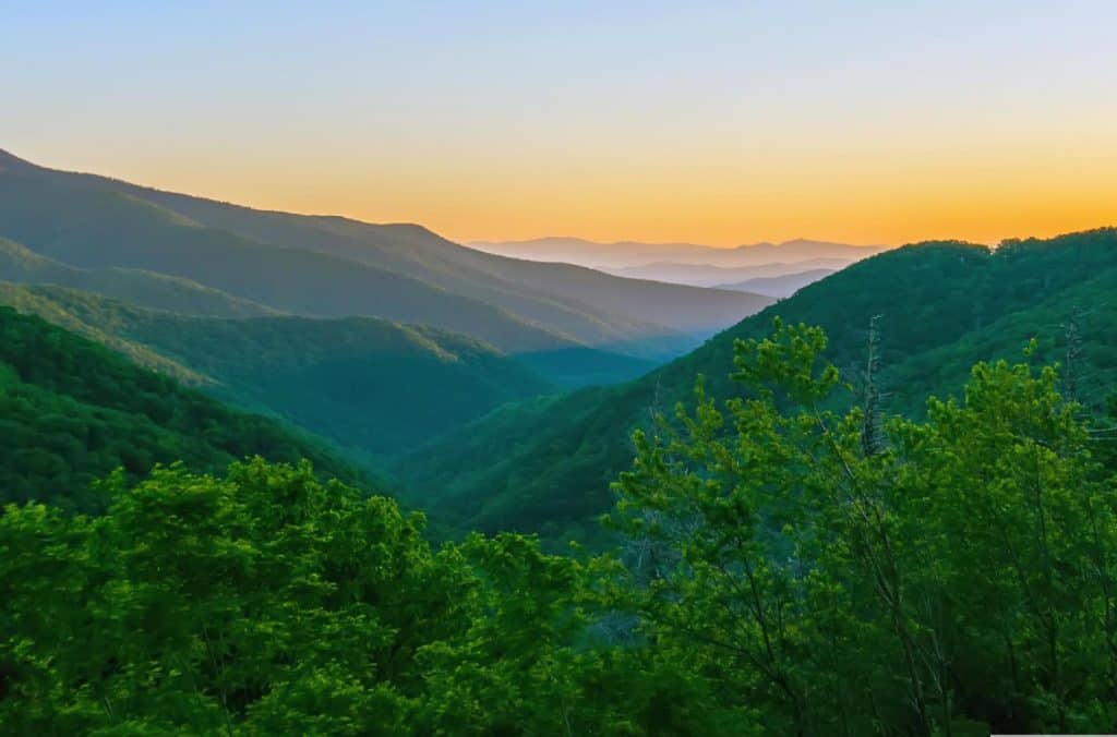 View of a grassy mountain range as the sun rises. 