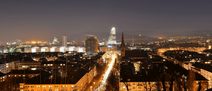 A city skyline at night, with cars rushing on the road.