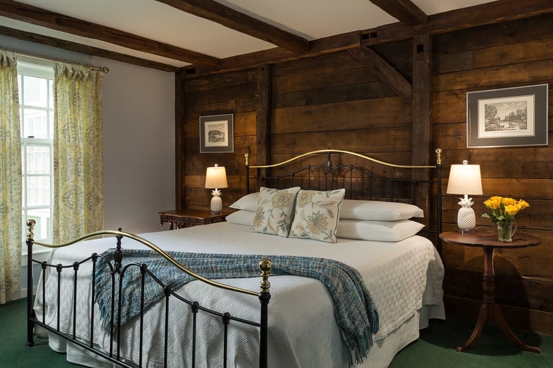 A bed is made in a wooden room.