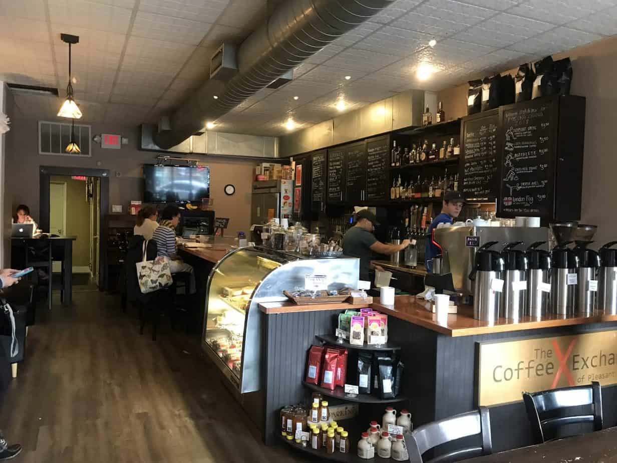 Baristas work in a cafe while people sit at the counter.