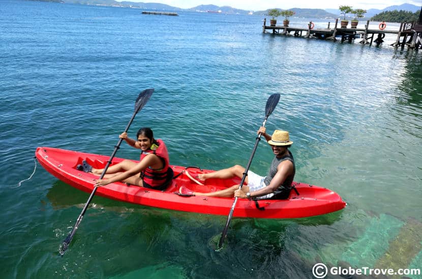 A couple kayaking on the water in a red boat.