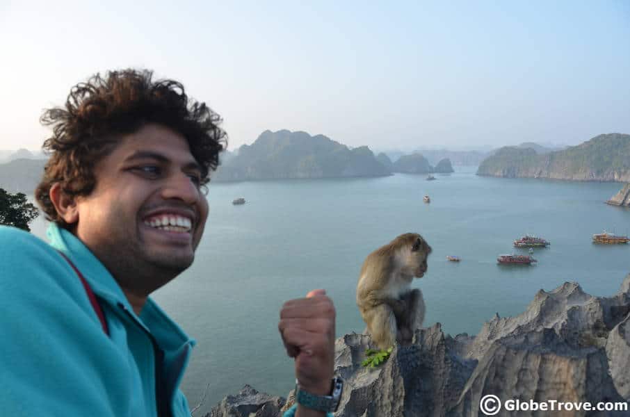 Man smiling while pointing to a monkey near the water.