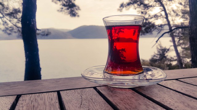 Close up of a red drink with a view of the ocean behind.