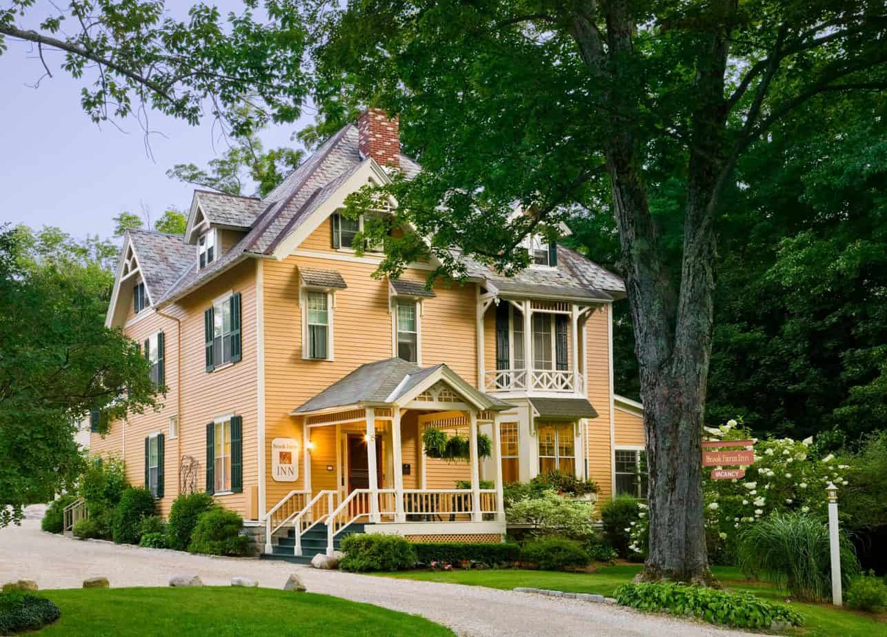 A big yellow home with a walkway leading to it.