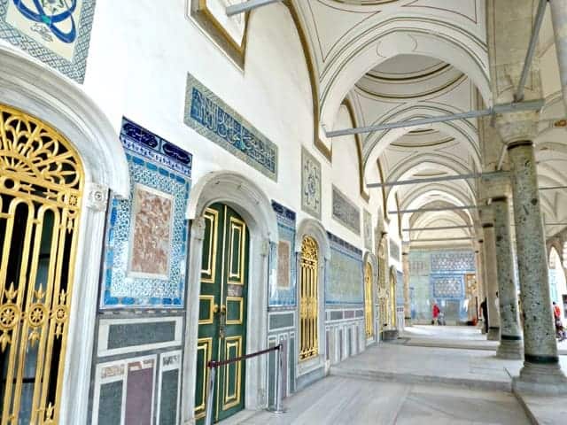 Exterior of a building with blue, green, and yellow mosaic walls. 