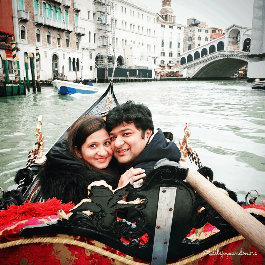 A couple hugs one another on a gondola on the water