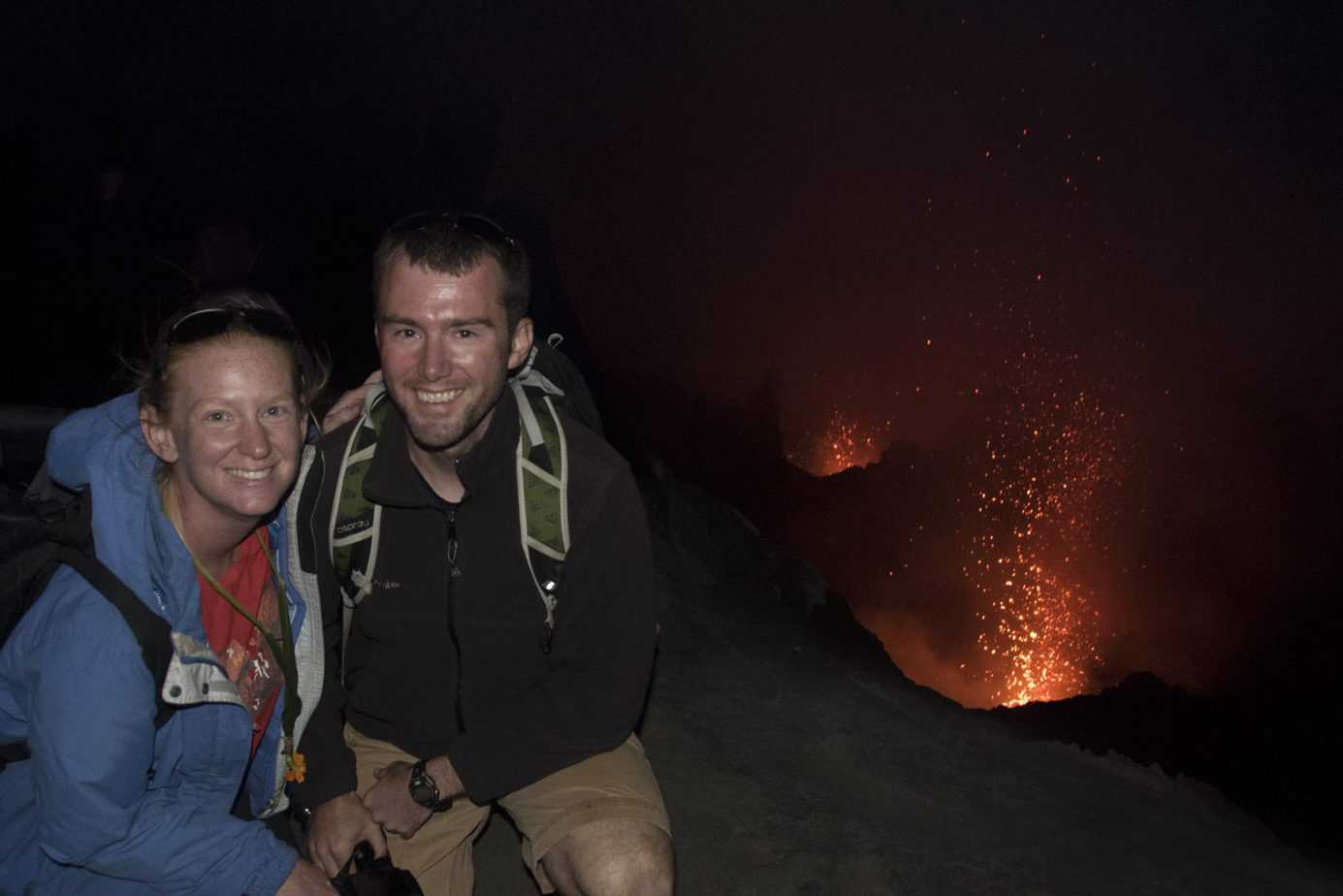 A couple smiles near an active volcano