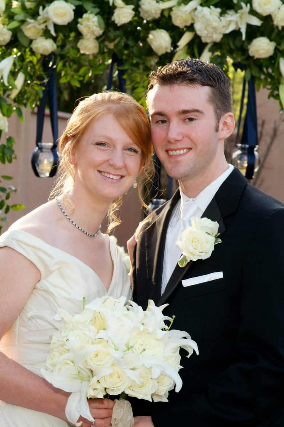 A couple in wedding outfits smile at the camera