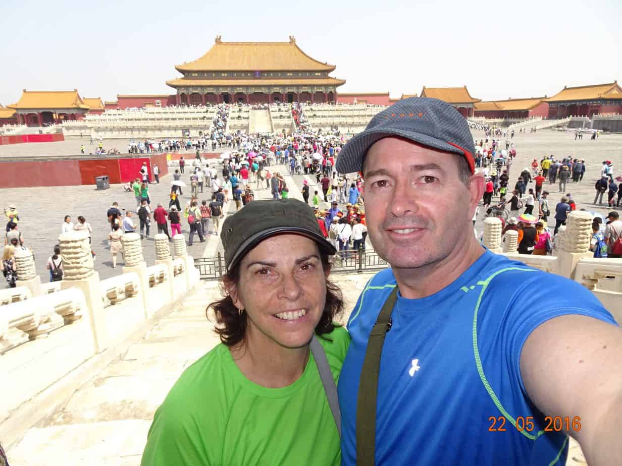 A couple smiles with lots of people in a plaza behind them.