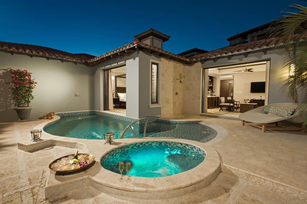 A romantic villa with a small pool and jacuzzi on an outdoor patio. 