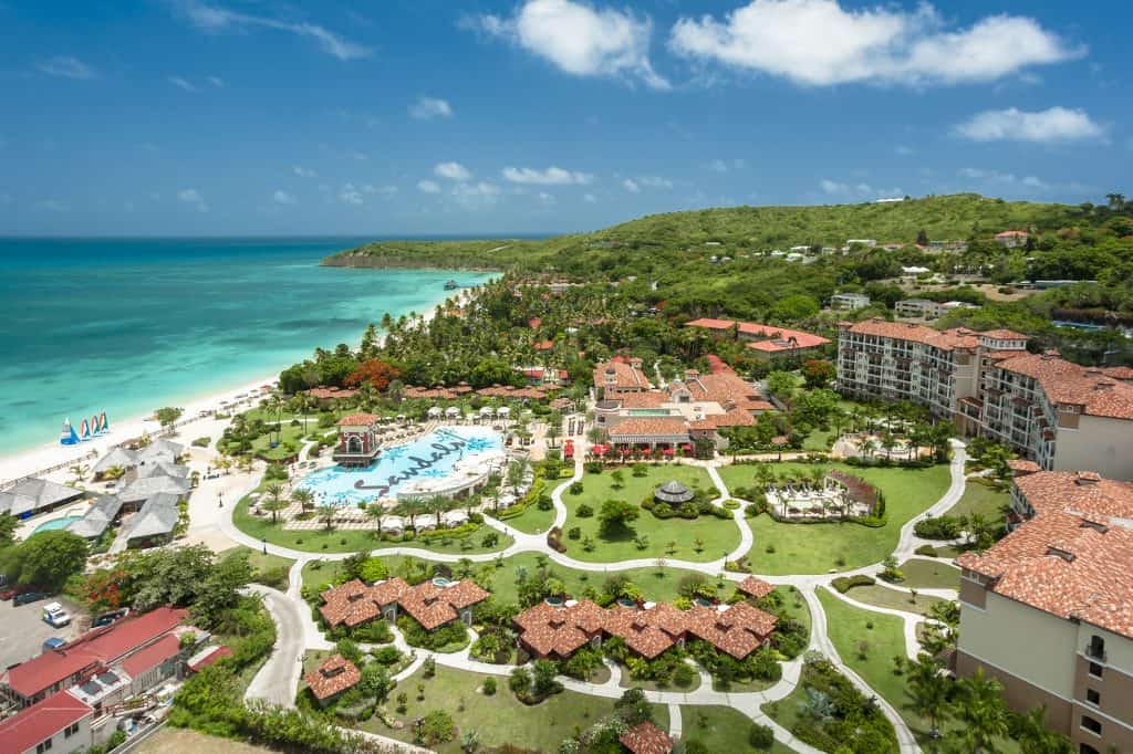 A luxury resort is seen with a beautiful sea foam green ocean on one side