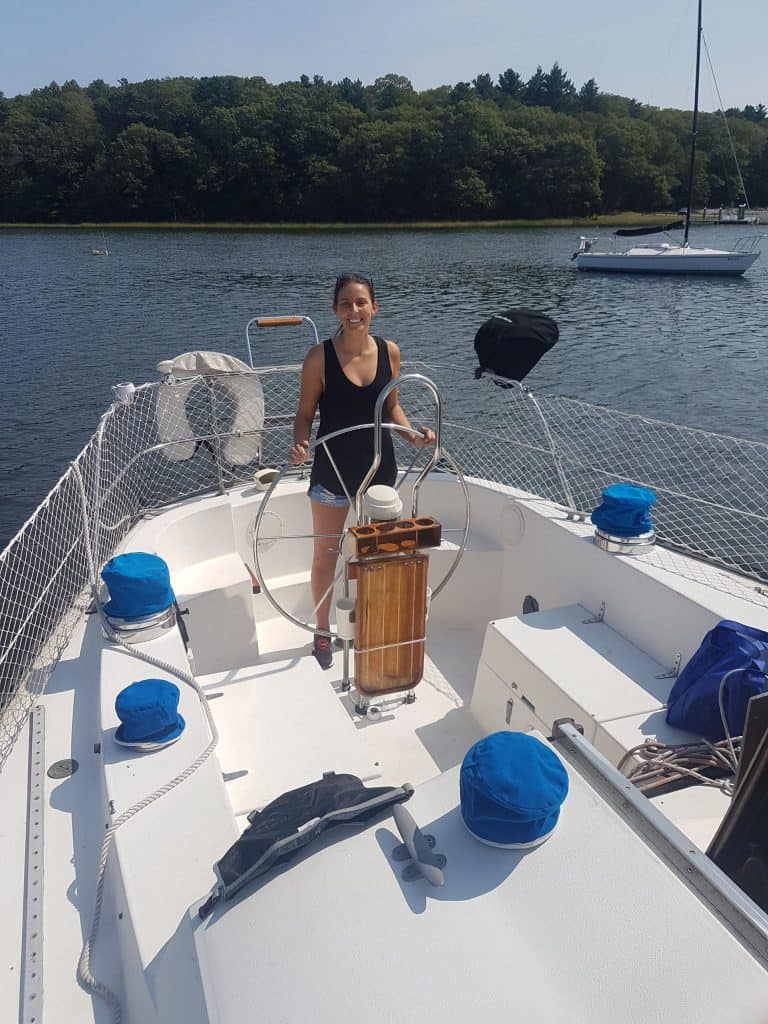 A woman steers a ship on the water.