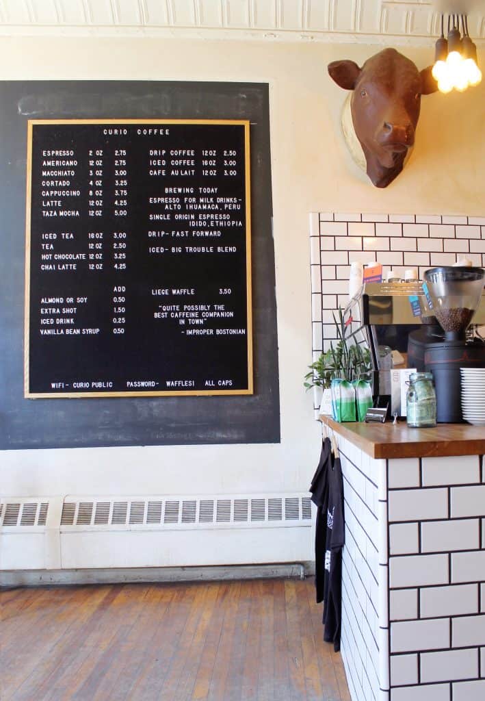 Close up of a black menu with white writing on a cafe wall.