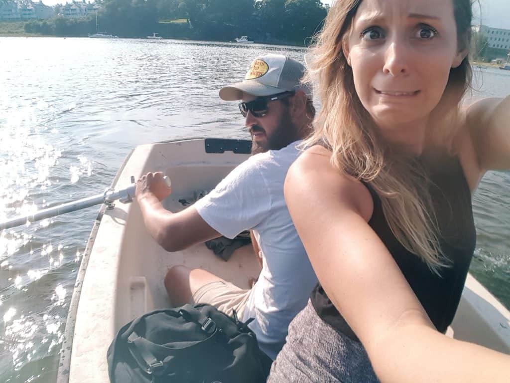 A couple smiles on a boat on the water.