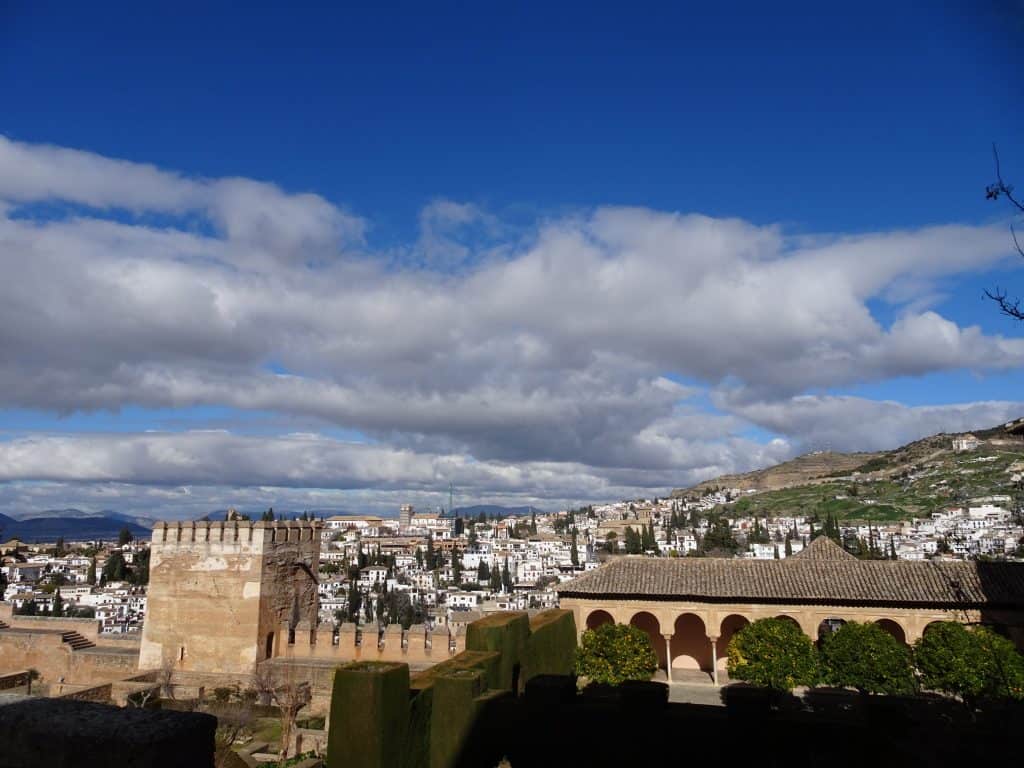 View of white buildings in a town in the distance surrounded by mountains.