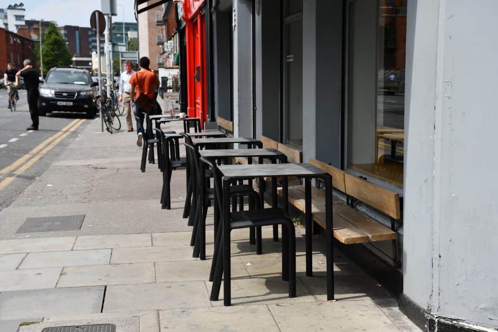 Black tables and chairs outside a cafe.