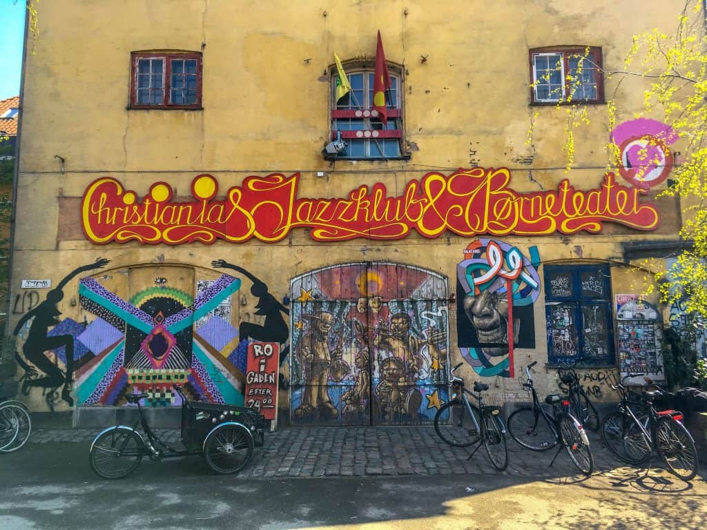 Bikes are parked in front of a shop covered in street art.