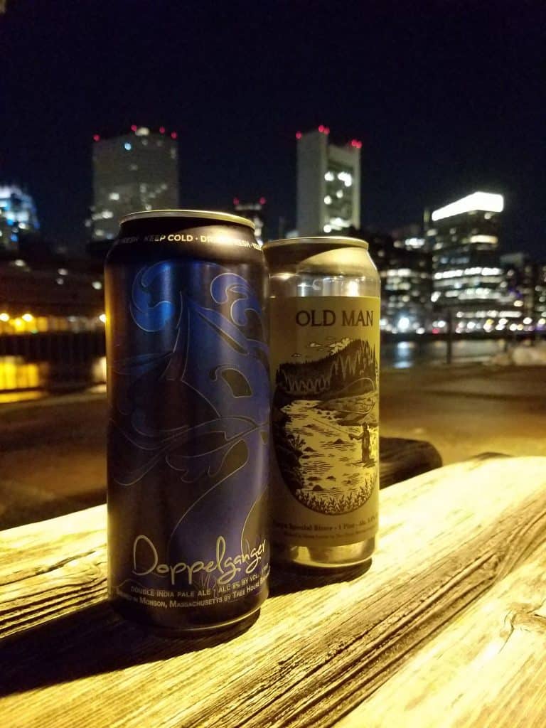 Close up of two cans of alcohol with a city skyline behind.