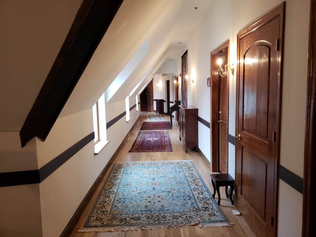 An empty hallway in a historic building lined with old rugs.