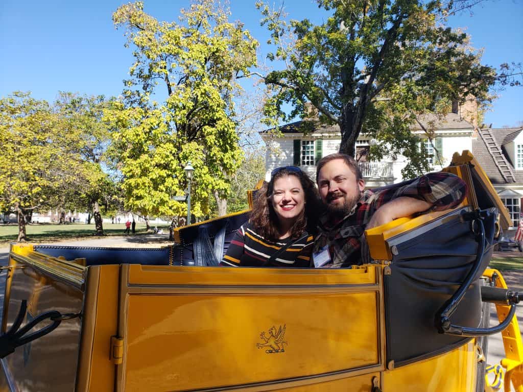 A couple sits smiling inside a yellow carriage.