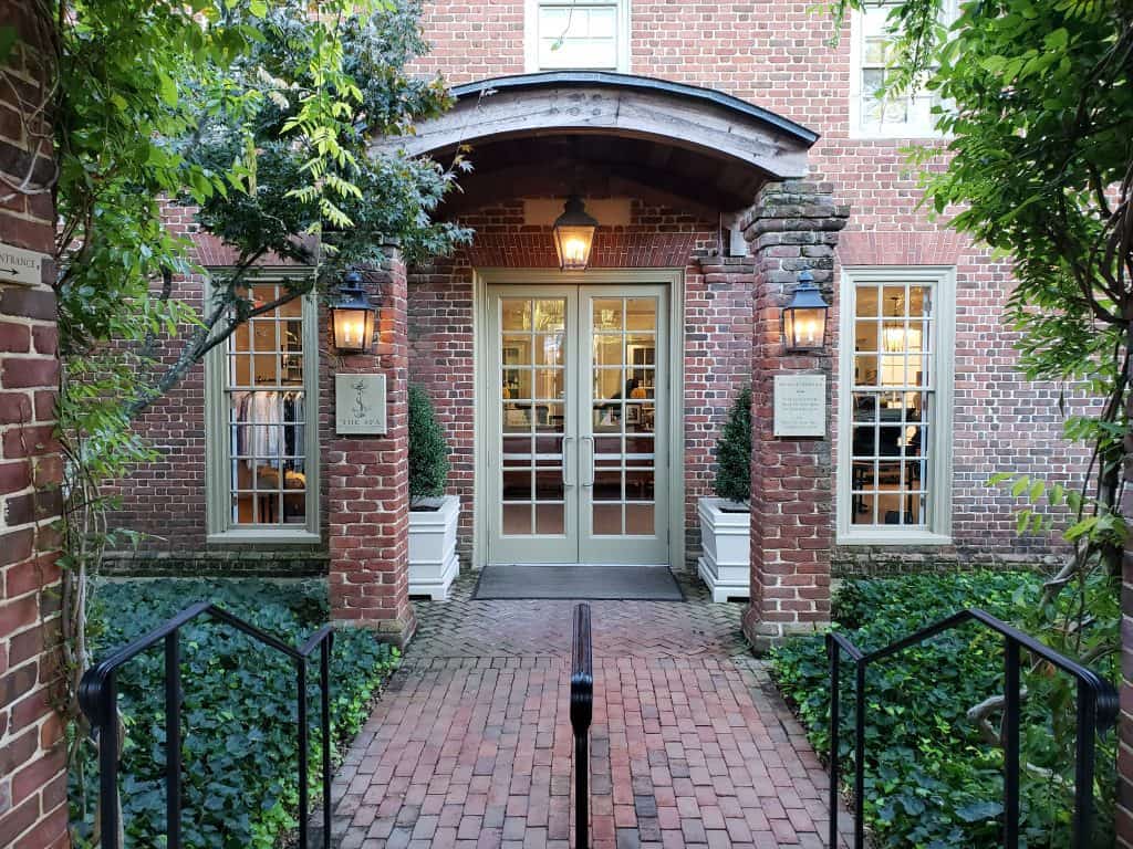 A brick pathway leads to the entrance of a brick building with a green doorway.