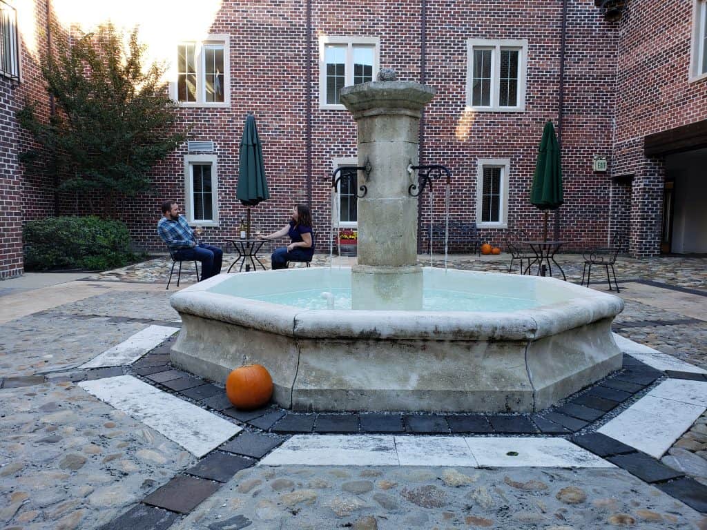 A fountain spews water while a couple sits at a table nearby