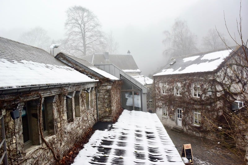 A small hamlet is dusted in snow and is surrounded by fog.