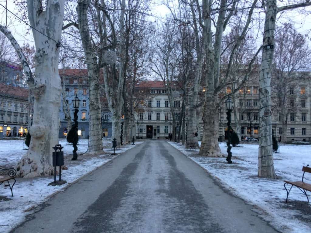 A charming empty lane in winter leads to a line of storefronts.