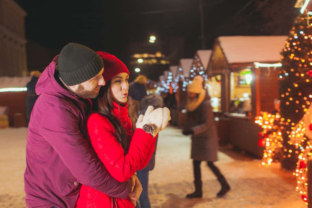 Winter portrait of married couple downtown at night Christmas fair on a holiday date night