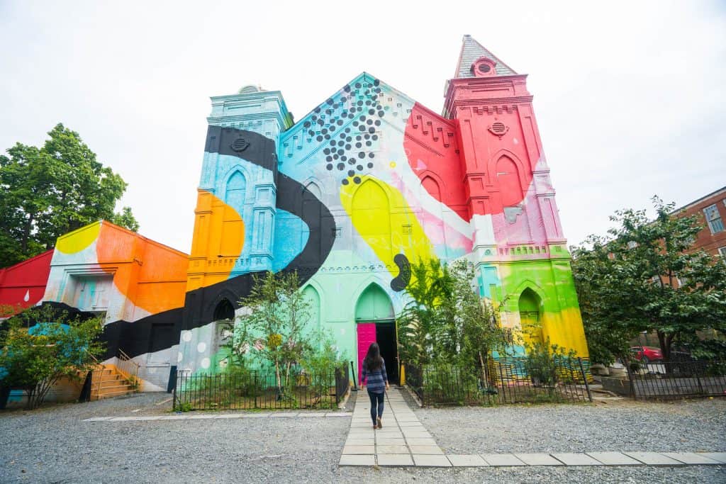 Person walking into a giant building with bright colors painted on the outside.